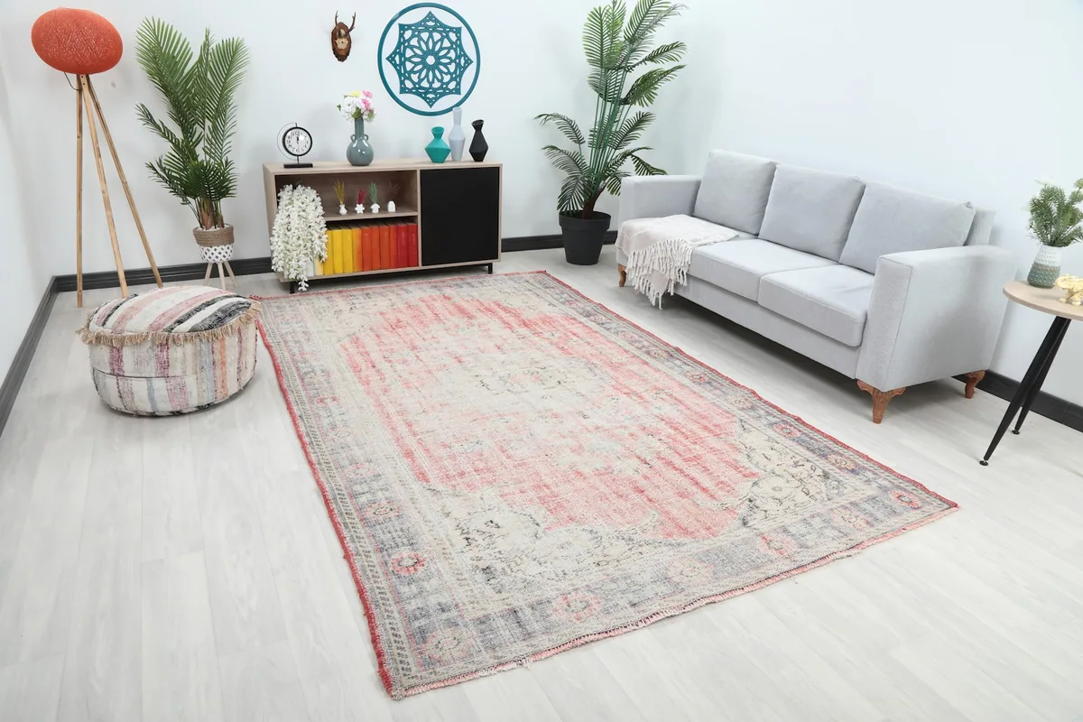 Angle view of the large rose and ivory rug complementing a gray sofa and light decor