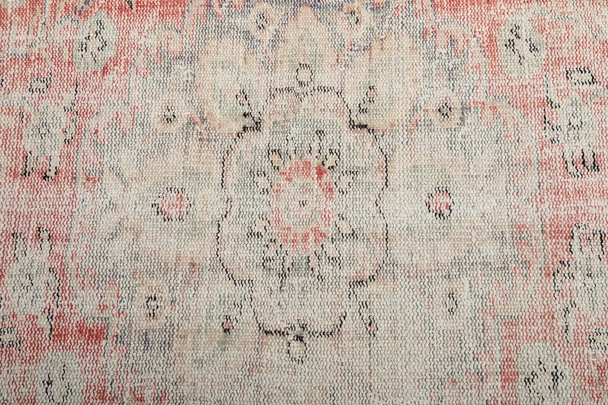 Close-up of the faded central medallion with subtle floral elements in rose and ivory
