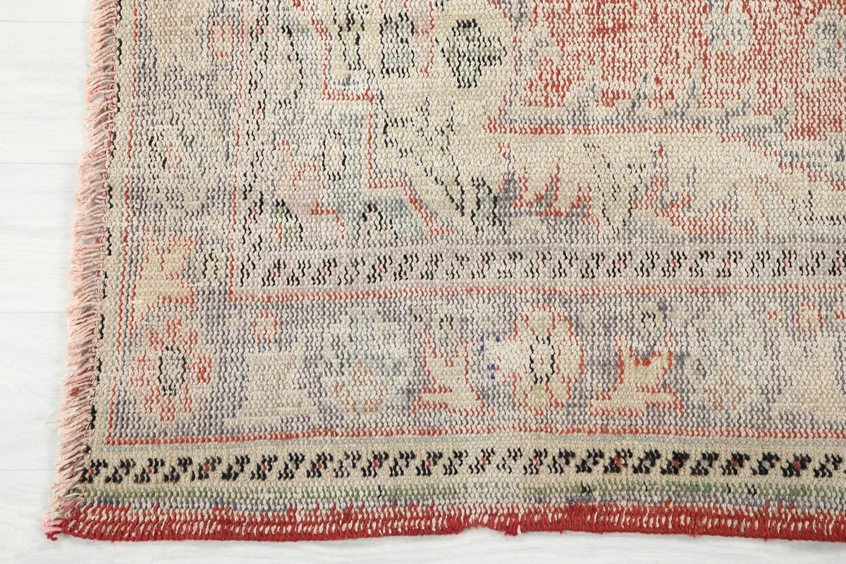 Detailed view of the rug's border design, showing the intricate hand-knotted work and fringe.