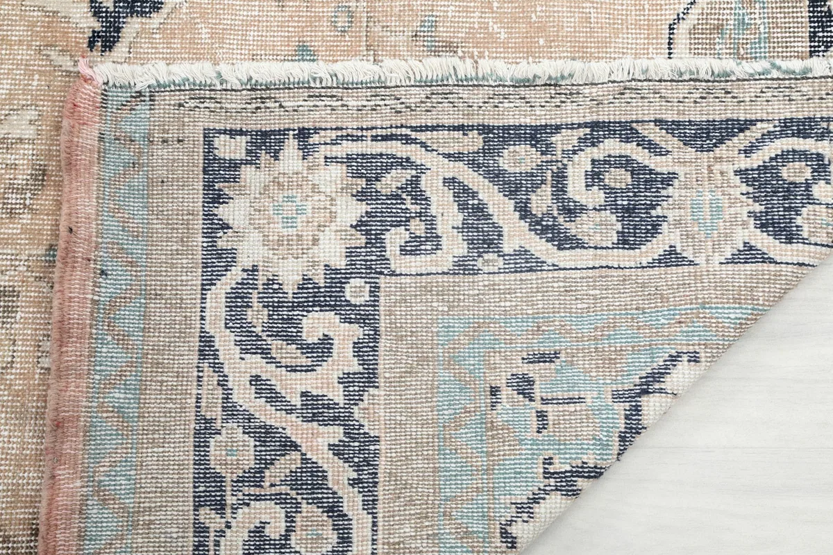 Close-up of the rug's border and fringe, showing the hand-knotted texture and colors