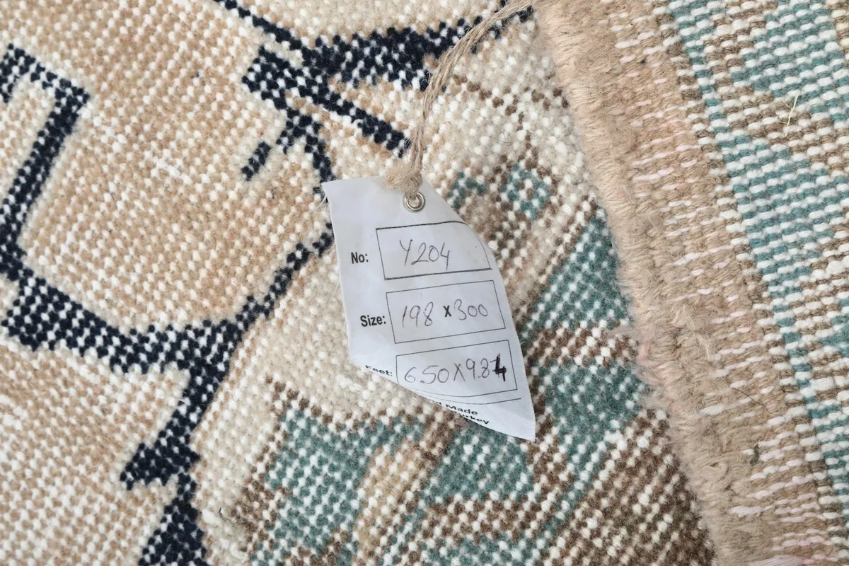 View of the rug's back with a size tag, showing the hand-knotted construction