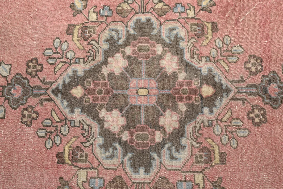 Close-up of a central medallion motif with charcoal, beige, and rose tones
