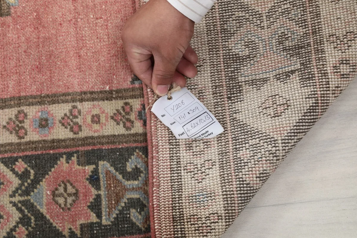Hand holding a tag with size information next to the rug's back