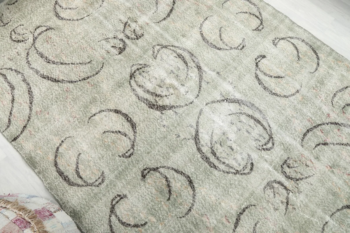 Overhead angle shot highlighting the abstract charcoal patterns across the green field of the vintage area rug.