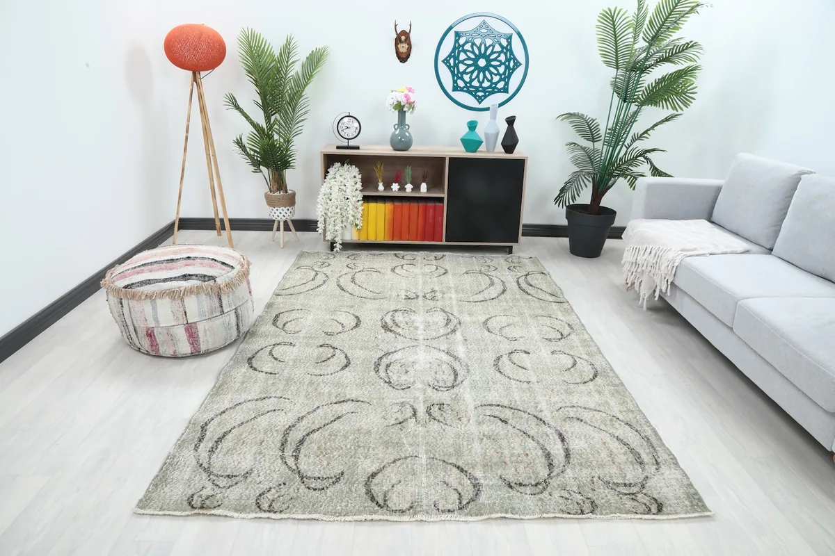 Vintage green area rug with charcoal abstract motifs in a modern living room setting with a gray sofa and plants.