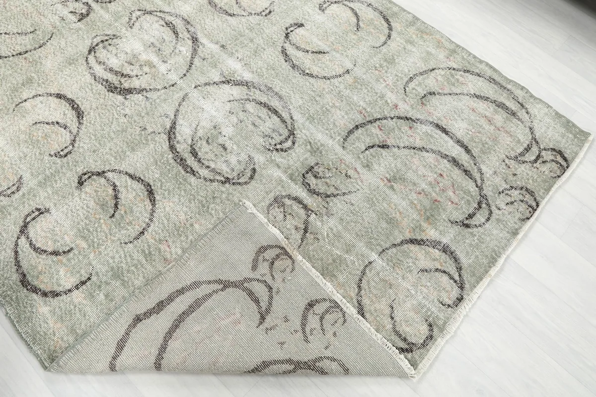 The green vintage rug folded to reveal the underside and the consistency of the abstract charcoal pattern.