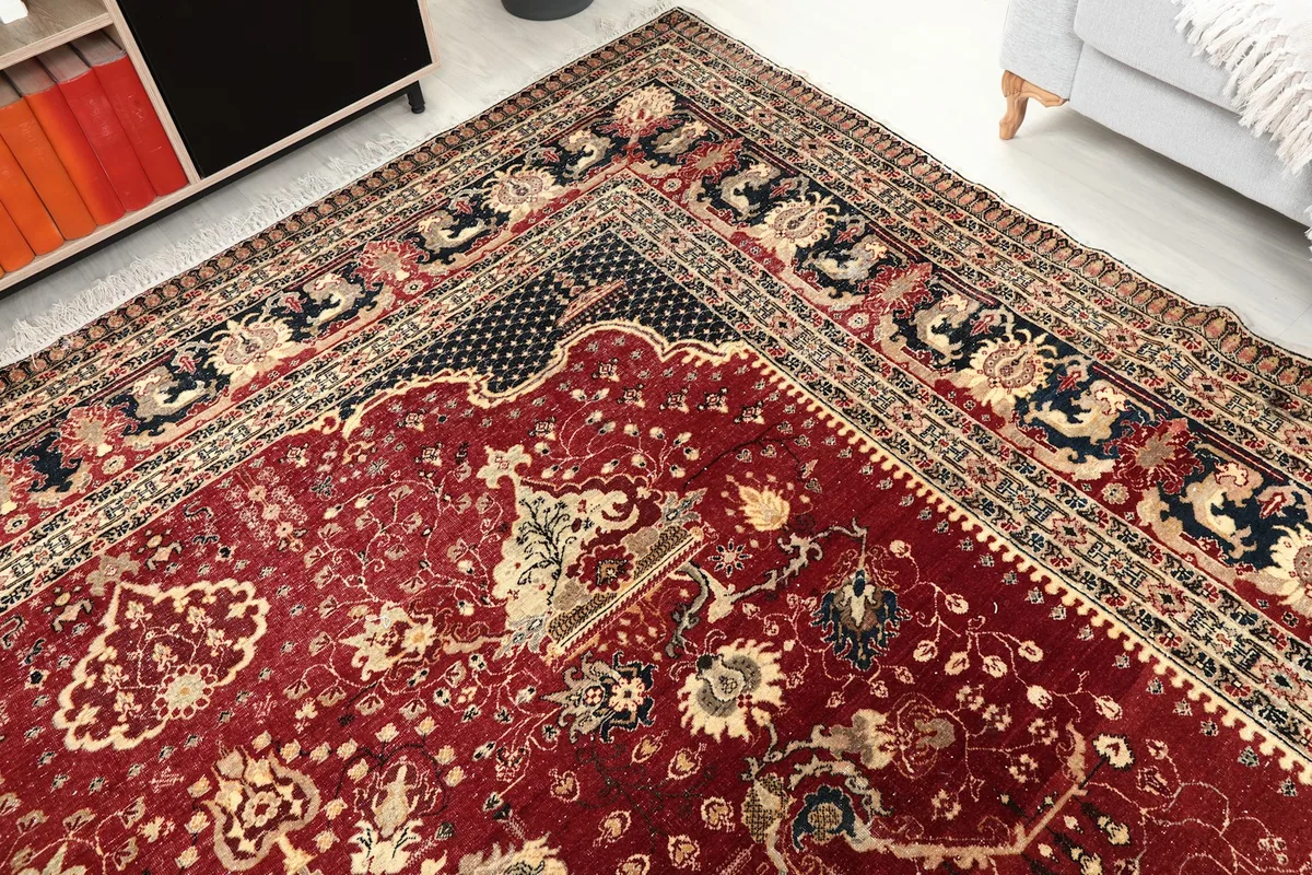 Close-up of a rug corner, displaying the navy border and red field transition