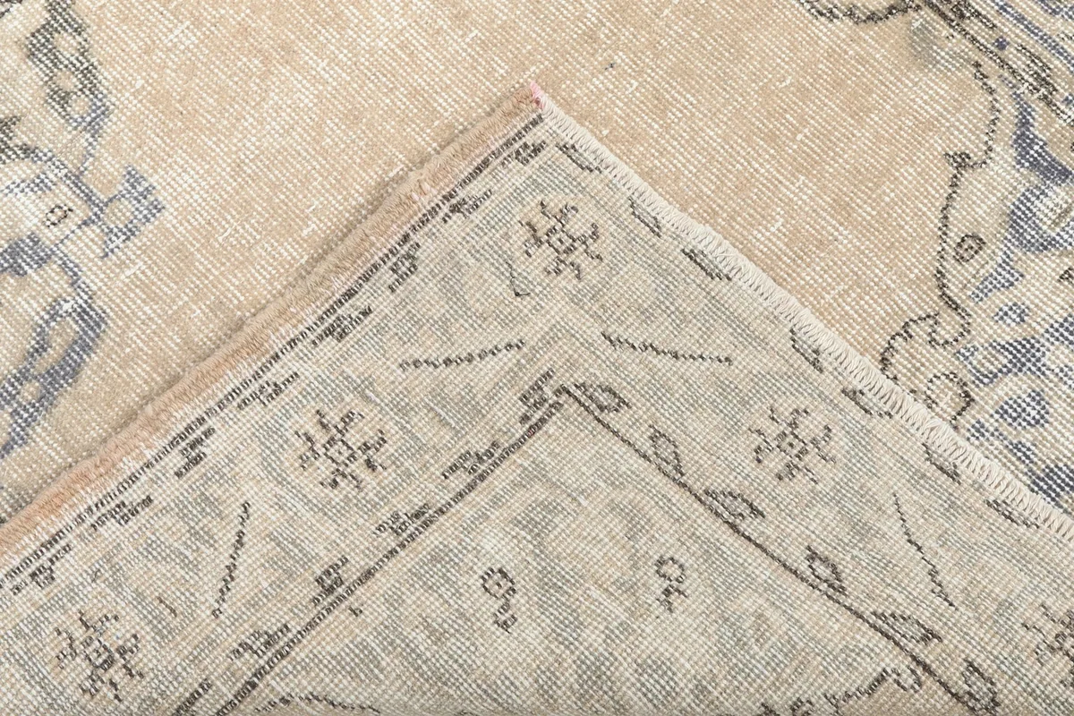 Corner of the rug folded back to show the hand-knotted cotton foundation and reverse side.