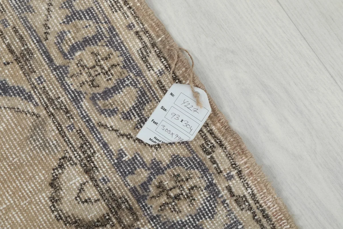 Close-up of the rug's edge with a product tag showing dimensions in centimeters.