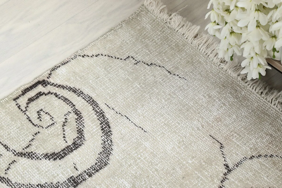 Corner detail of the rug, showing fringe and slight wear