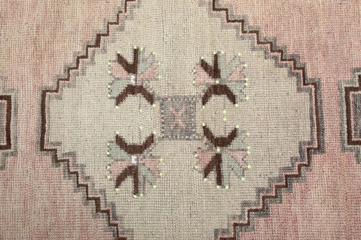 Detailed view of an ivory geometric medallion with brown and gray accents in the rug's center