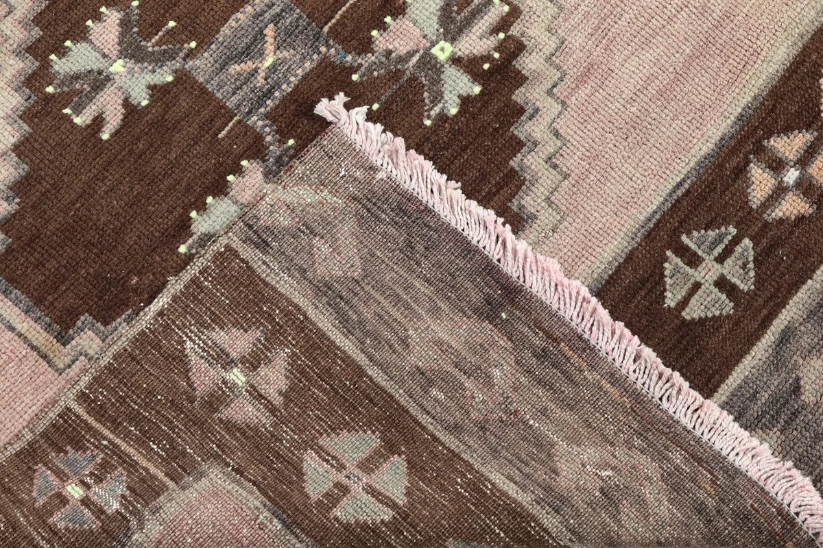 View of the back of the rug, revealing the hand-knotted construction and fringe