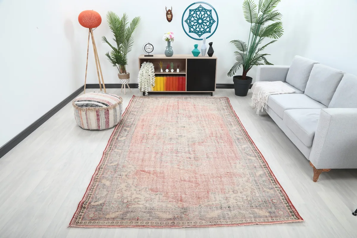 Vintage rose and gray rug in a living room setting with a light gray sofa and wooden furniture