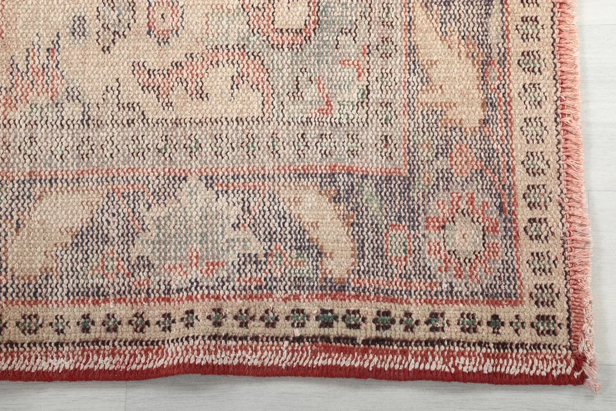 Detailed view of the intricate gray border and a corner of the rose field with short fringe