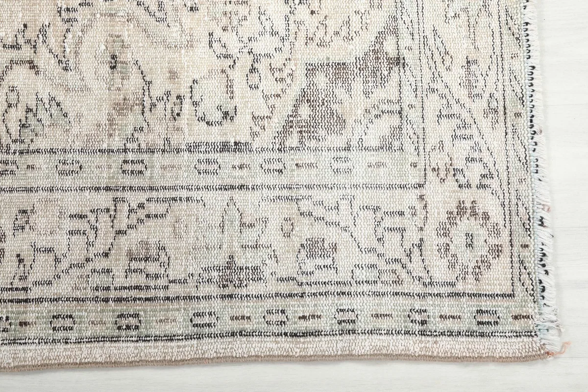 Detail of the gray border pattern and the edge of the vintage ivory rug