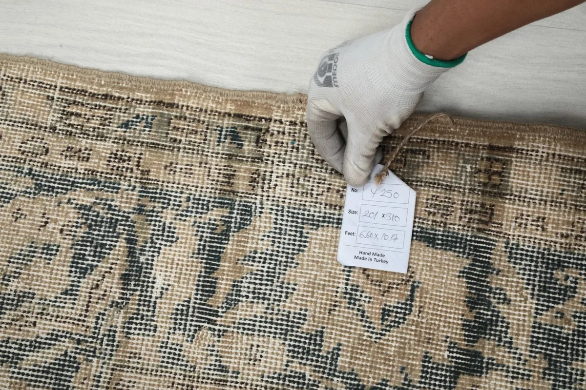 Hand holding a tag showing rug dimensions and origin on the rug surface