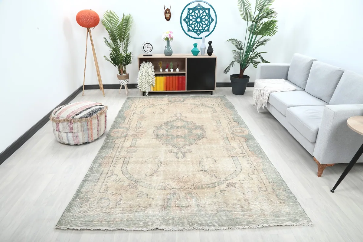Large ivory and green vintage rug laid out in a living room setting