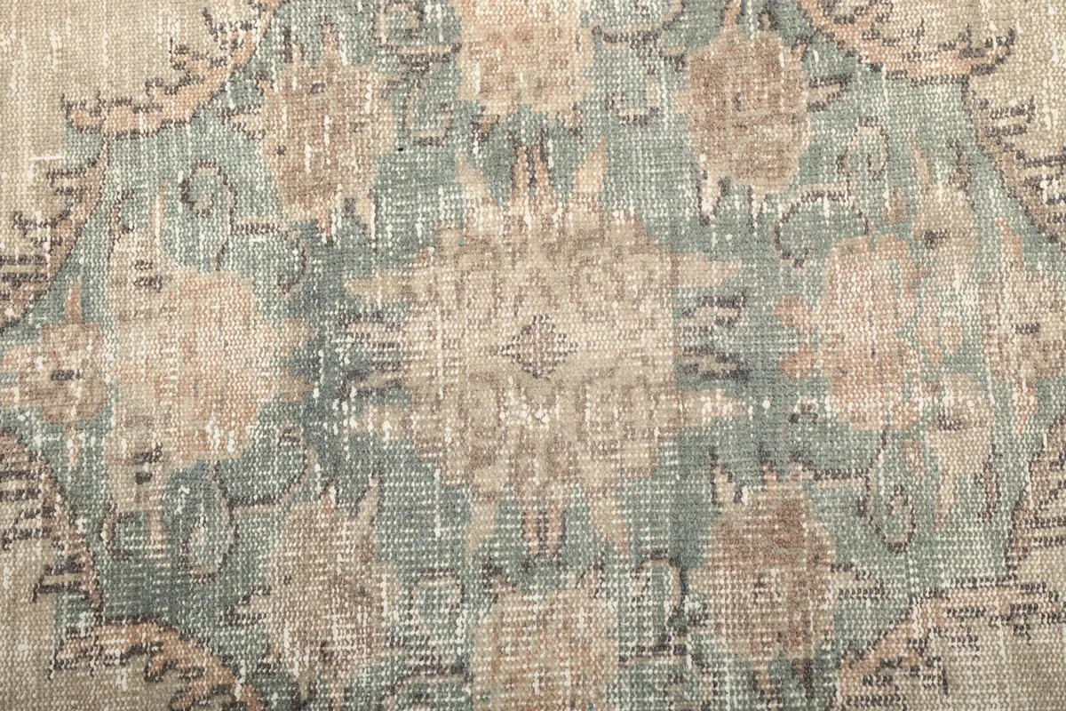 Close-up of the faded green and rust colors within the central medallion