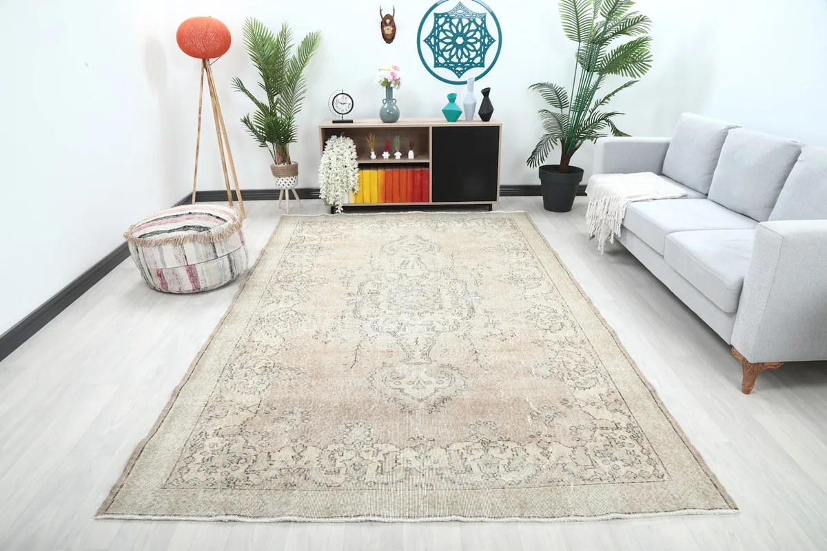 Large beige and ivory vintage rug placed in a modern living room setting