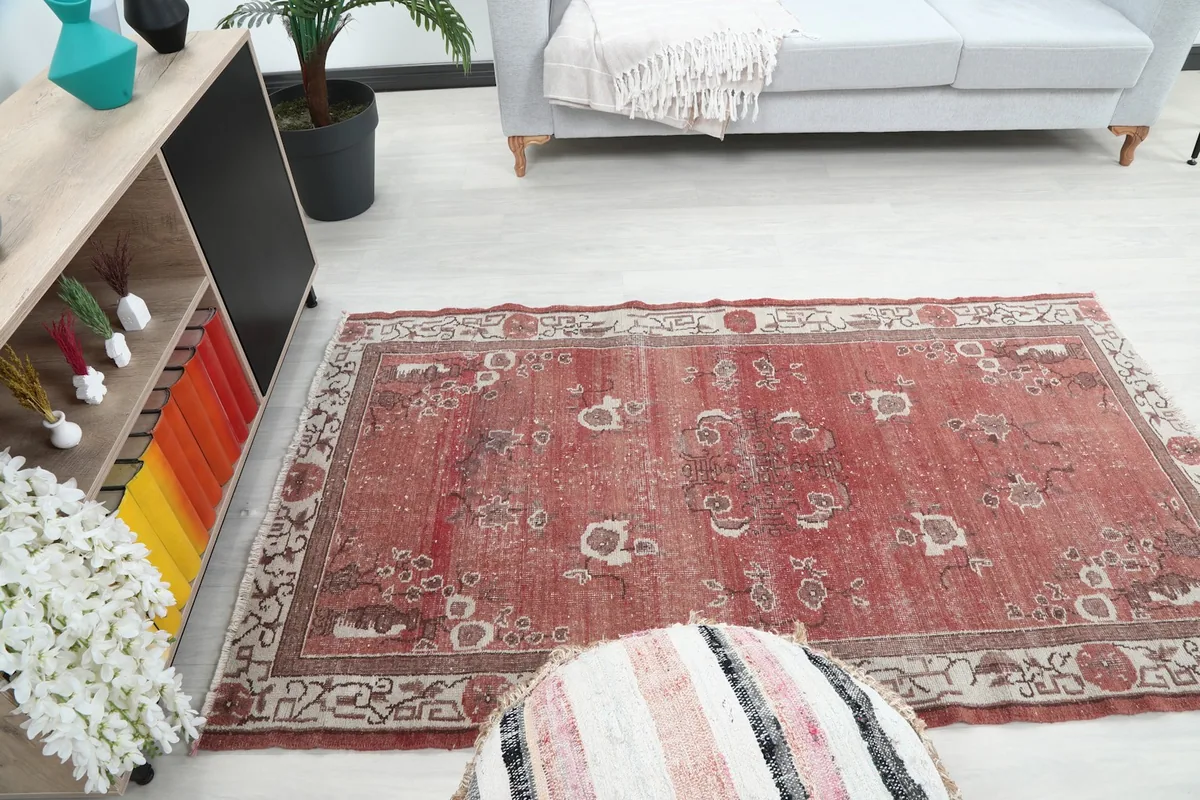 Rust floral rug placed in a living room, seen from a higher angle