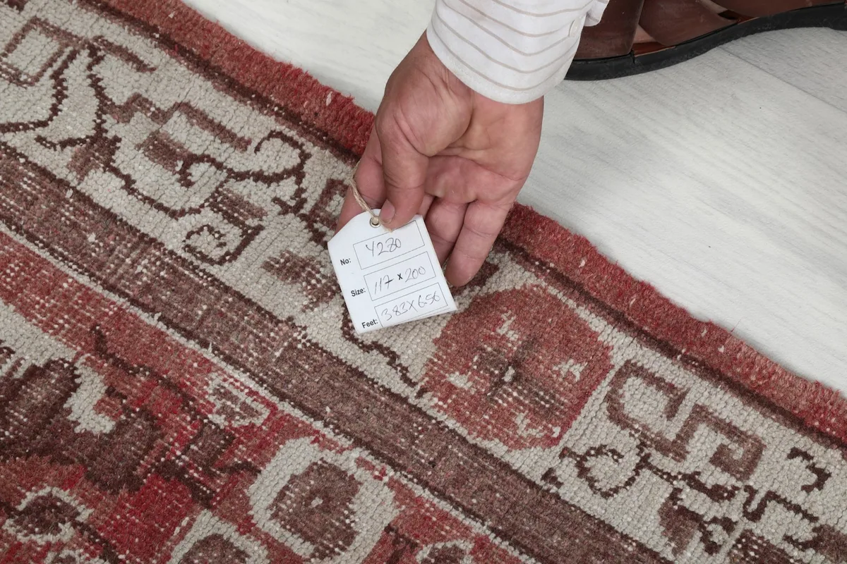 Hand holding a tag on the rug, showing the quality and authenticity