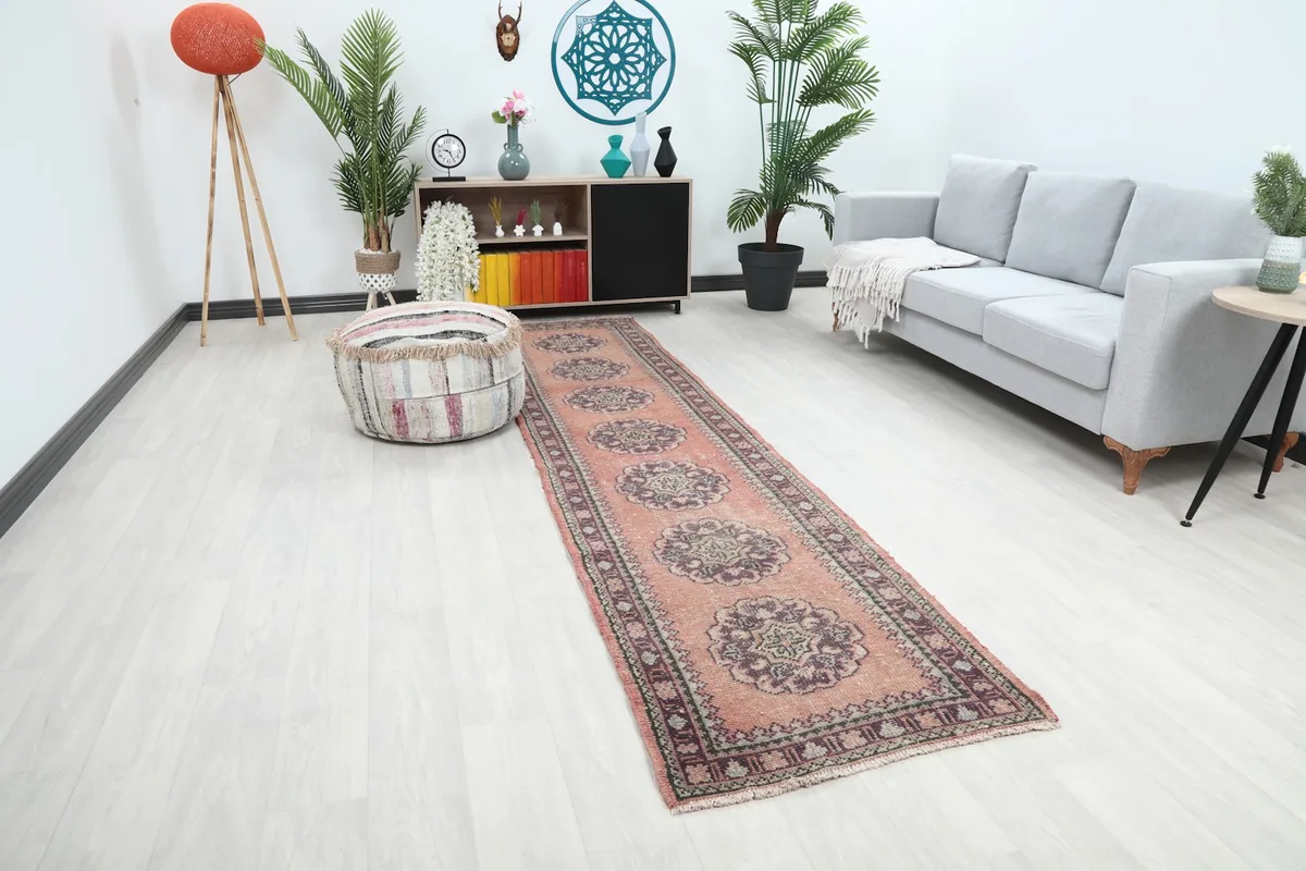 Angle view of the rose runner rug in a long room with a sofa and plants