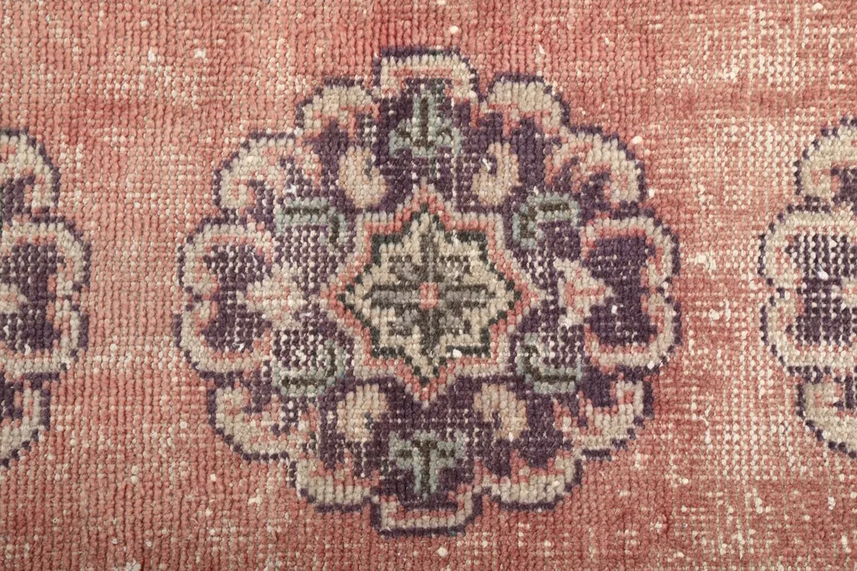 Close-up of a single purple and green medallion motif on the rose field