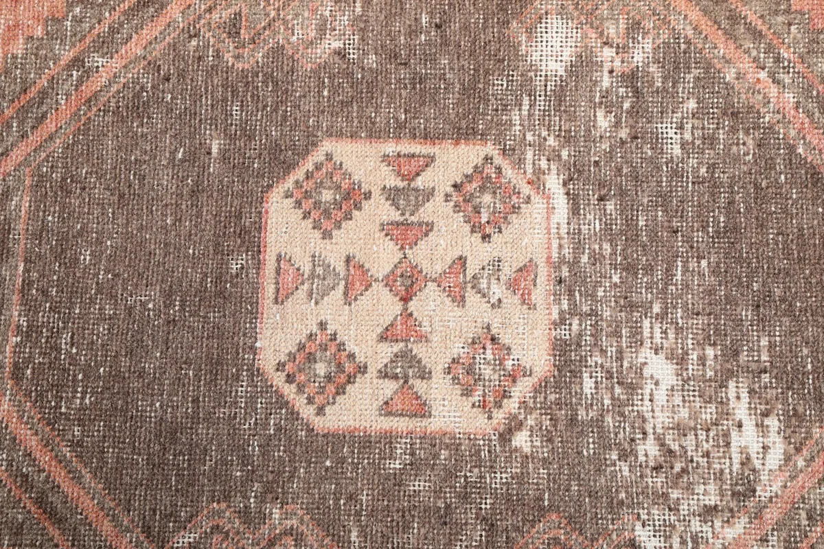 Close-up of the intricate central motif within a brown geometric medallion, showing beige and rust tones