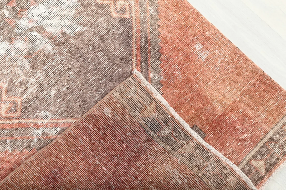 Folded corner of the rug revealing the wool pile on the front and the cotton foundation on the back