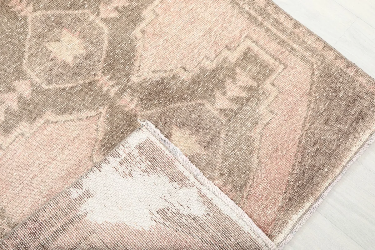 Folded corner of the rug, showing the front pattern and the reverse side with its cotton foundation.