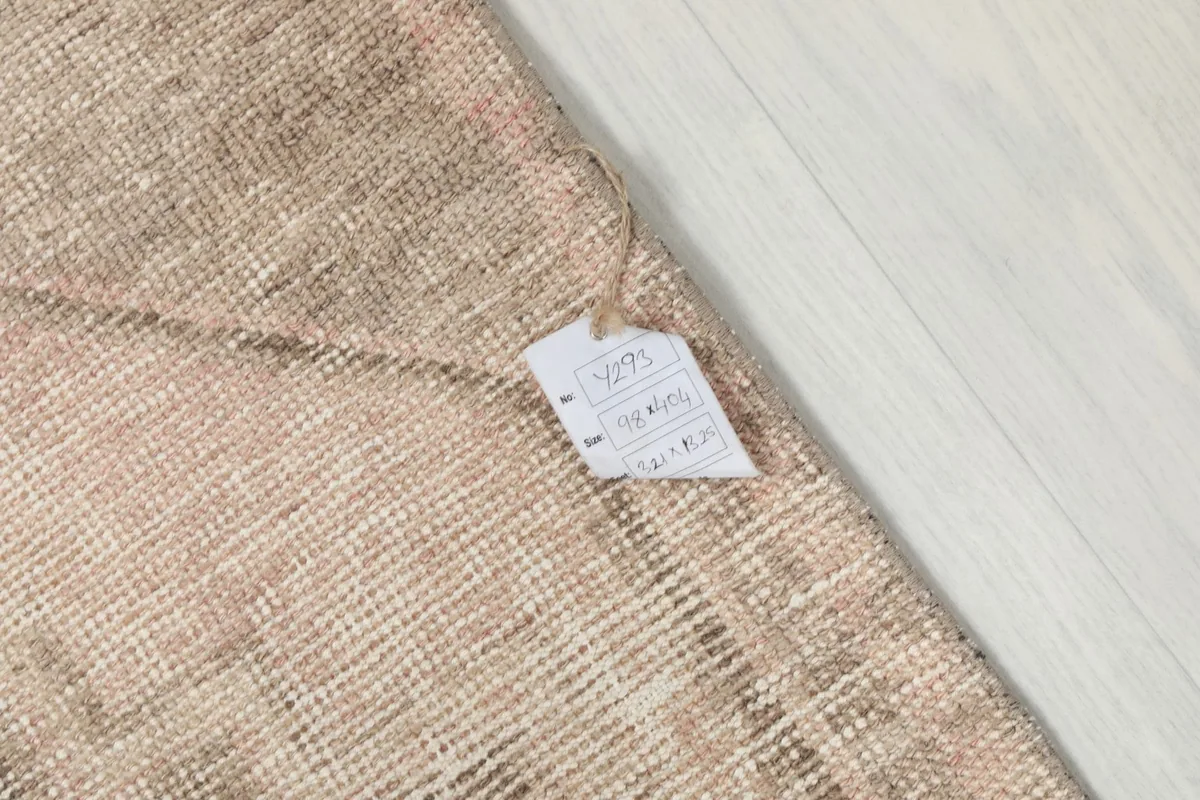 Close-up of the rug's back with a product tag, showing the hand-knotted texture.