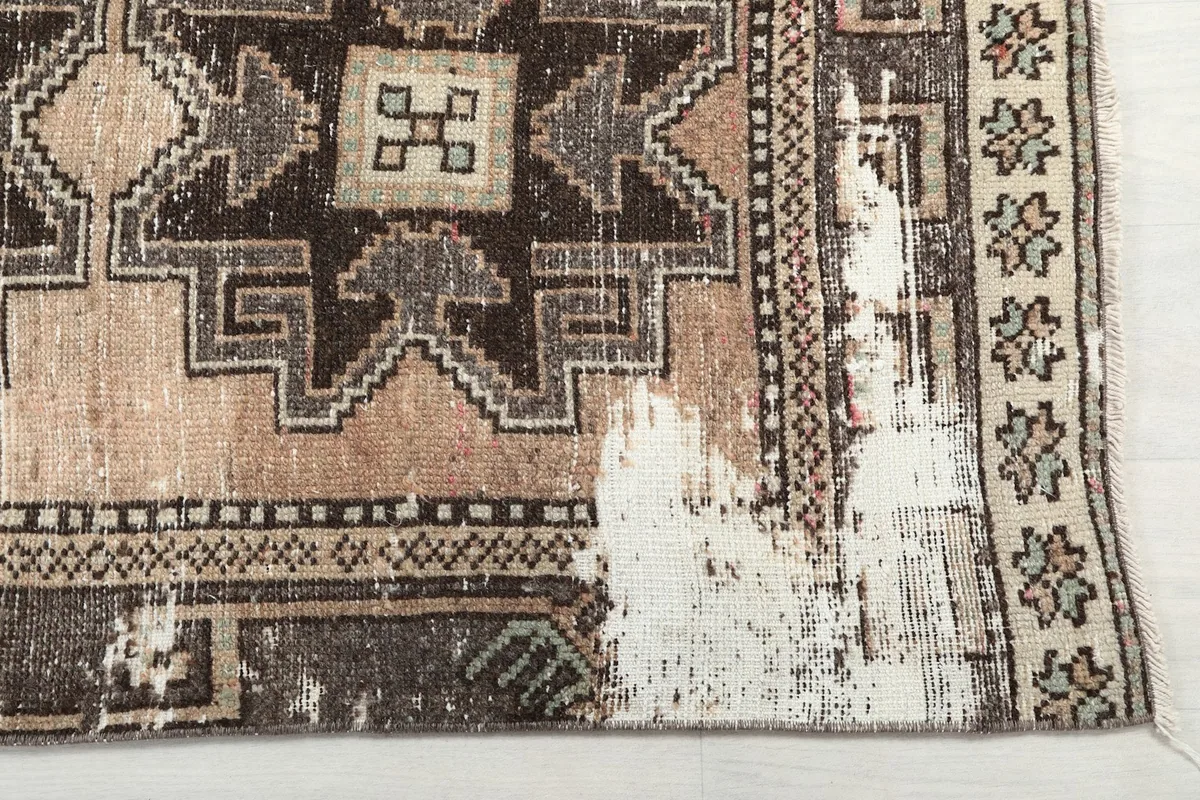 Detailed view of the rug's border and a worn area, showing the underlying foundation