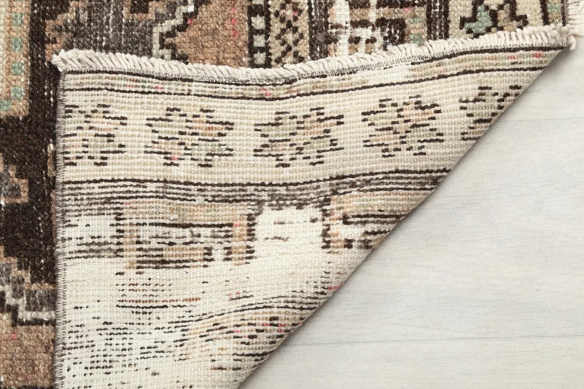 Close-up of the rug's fringe and a folded corner, showing the back of the weave