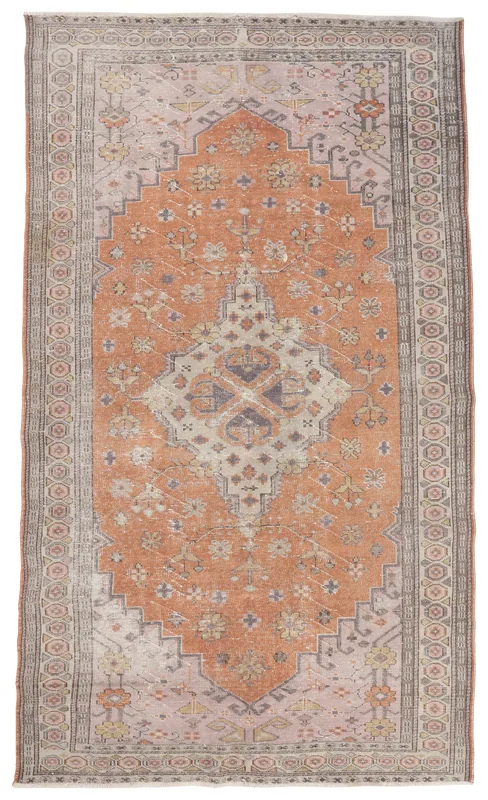 Full overhead view of a vintage orange and gray Anatolian area rug with a central medallion.