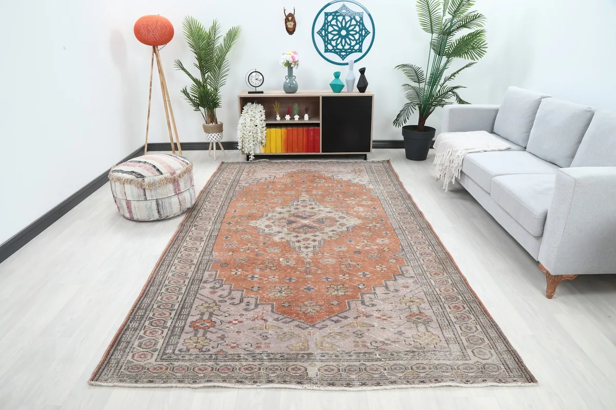 Large orange and gray vintage rug placed in a modern living room setting with a light sofa.