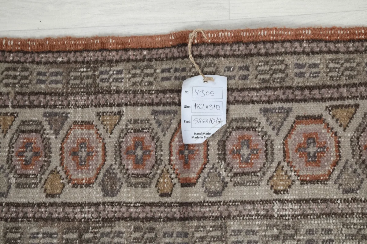 Close-up of the rug's border showing the care tag, indicating hand-knotted wool.