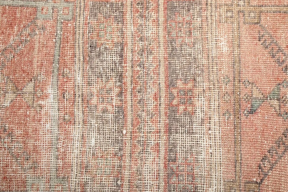 Close-up of the low wool pile, revealing the hand-knotted texture and faded rose, brown, and gray threads.