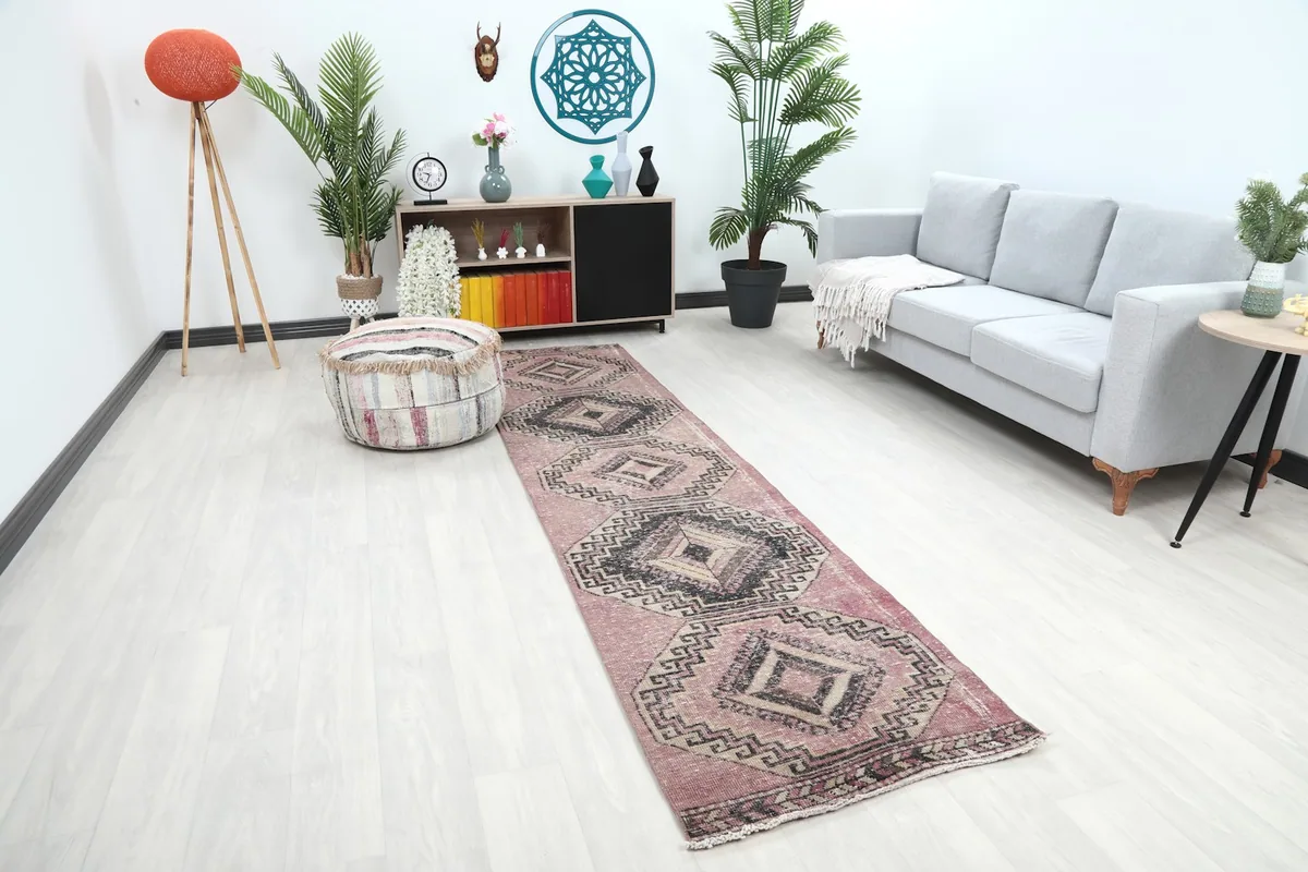 Angle view of the rose runner rug in a room, highlighting its placement next to a sofa and ottoman.