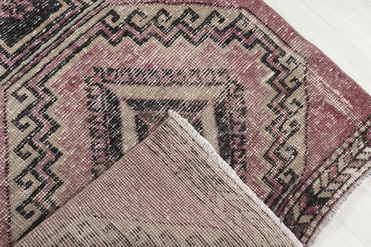 Folded corner of the rug, revealing the wool pile on cotton foundation and the reverse side of the pattern.