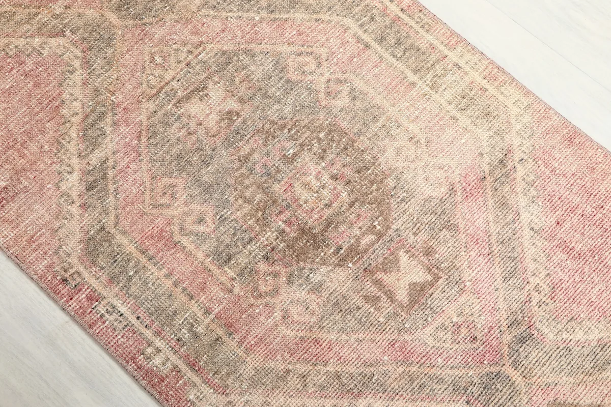Detailed view of the central gray and beige geometric medallion on the rose runner