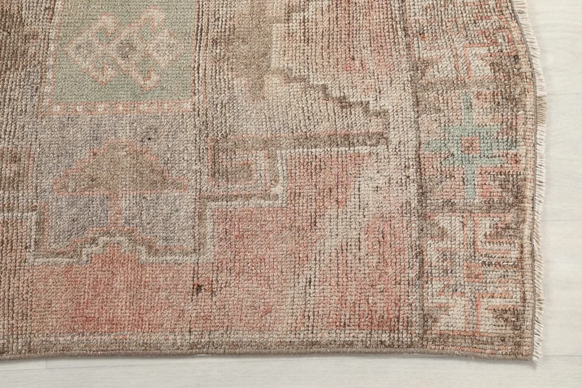 Close-up of the rug's edge, showing the subtle border design and the texture of the vintage wool.