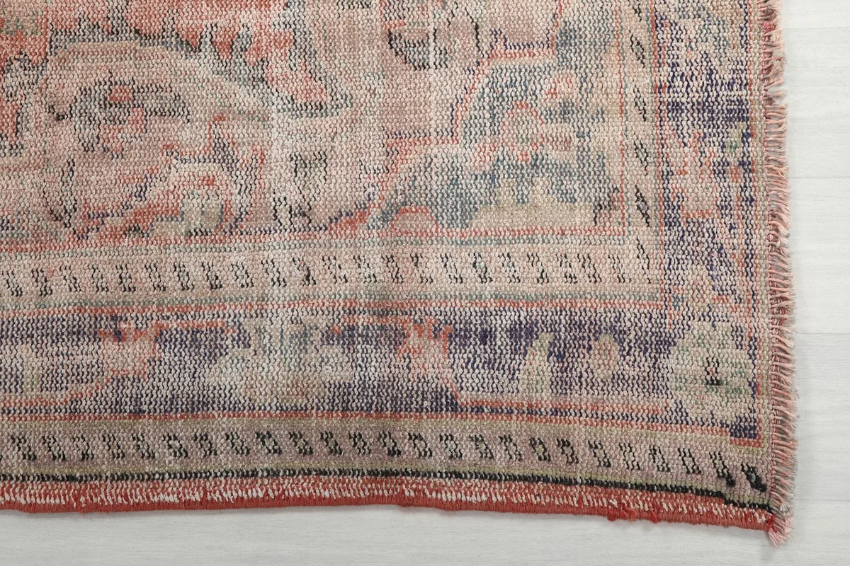 Detail of the patterned border and corner of the vintage rust and blue area rug