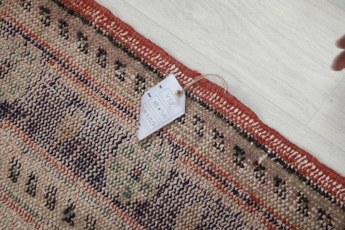 Close-up of the rug's edge and label, showing the hand-knotted detail