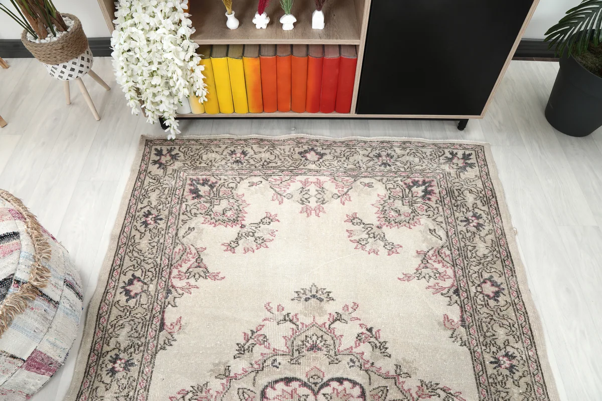 Top-down view of the Ivory Rose Medallion Anatolian Rug in a room, focusing on the upper half of the rug.