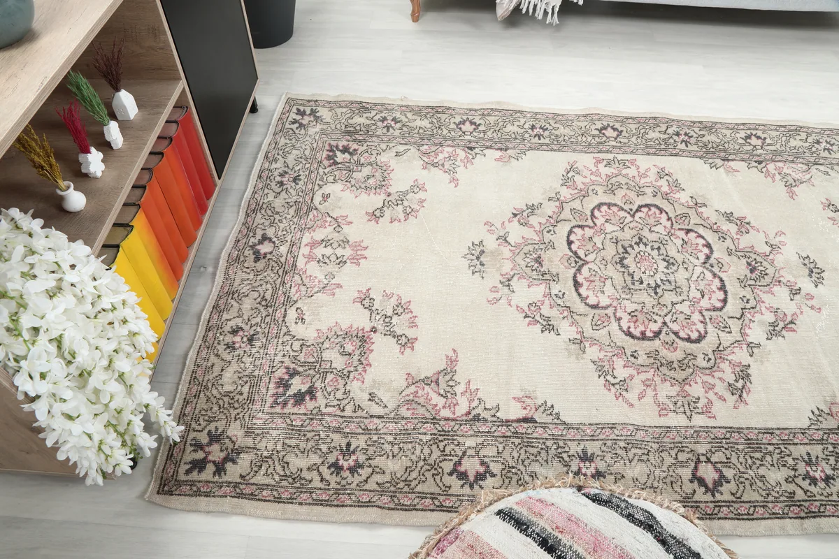 Wide angled view of the Ivory Rose Medallion Anatolian Rug in a room, showing its full length.