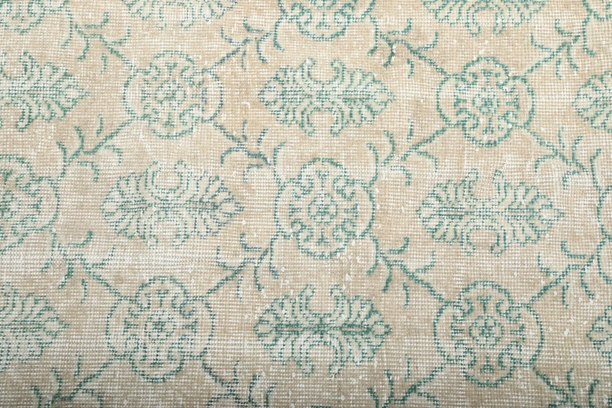 Detailed view of the hand-knotted wool pile and the intricate green motifs