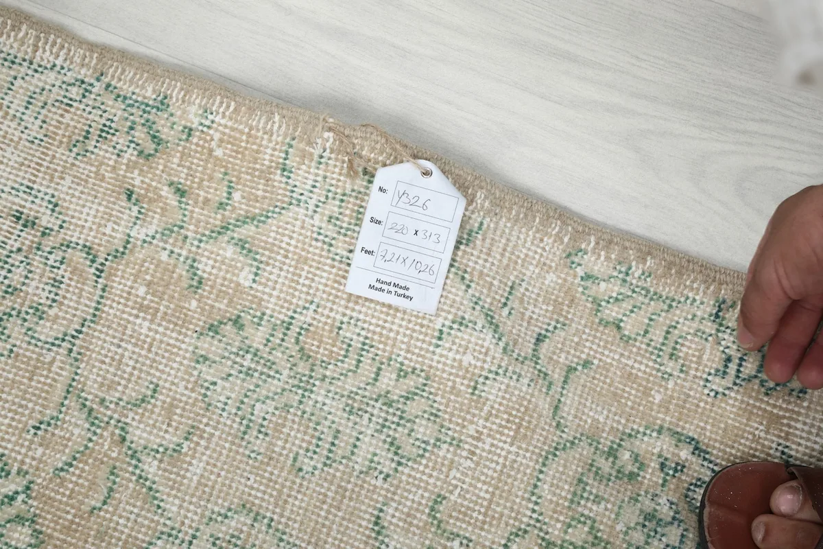 Hand holding a tag on the back of the rug, showing details and origin