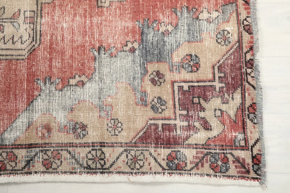 Detailed view of the rug's corner showing the border design and faded red and gray areas