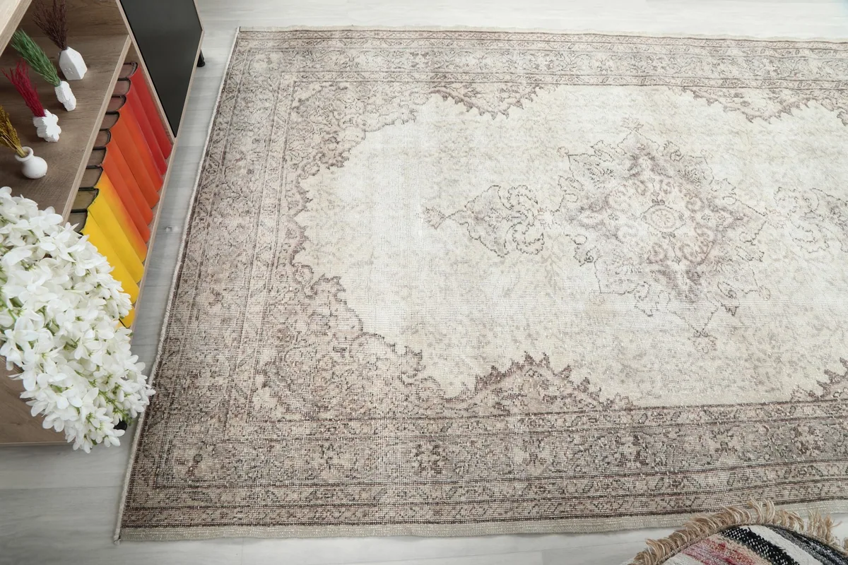 Top-down angle view of the rug, focusing on the border and field patterns near a piece of furniture.