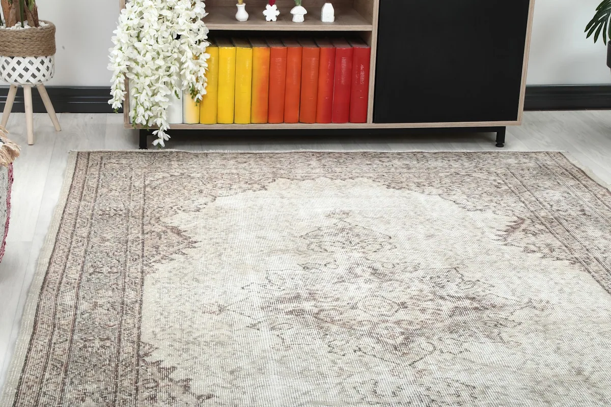 Close-up view of the vintage rug's corner and pattern next to a cabinet with colorful books.